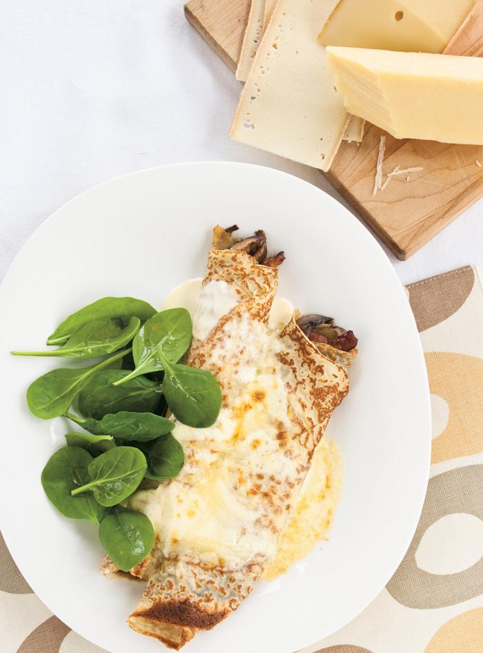 two mushroom crepes rolled in a white plate with spinach